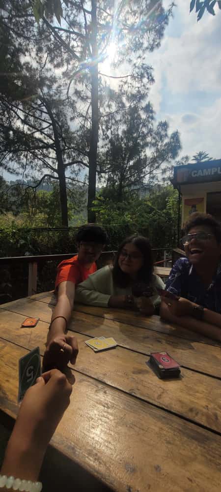 Students playing cards outdoors at Shoolini campus